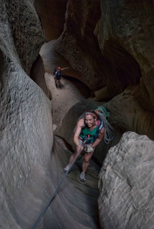 Kate Feller rappeling in Mystery Canyon with Megan Porter looking on.
